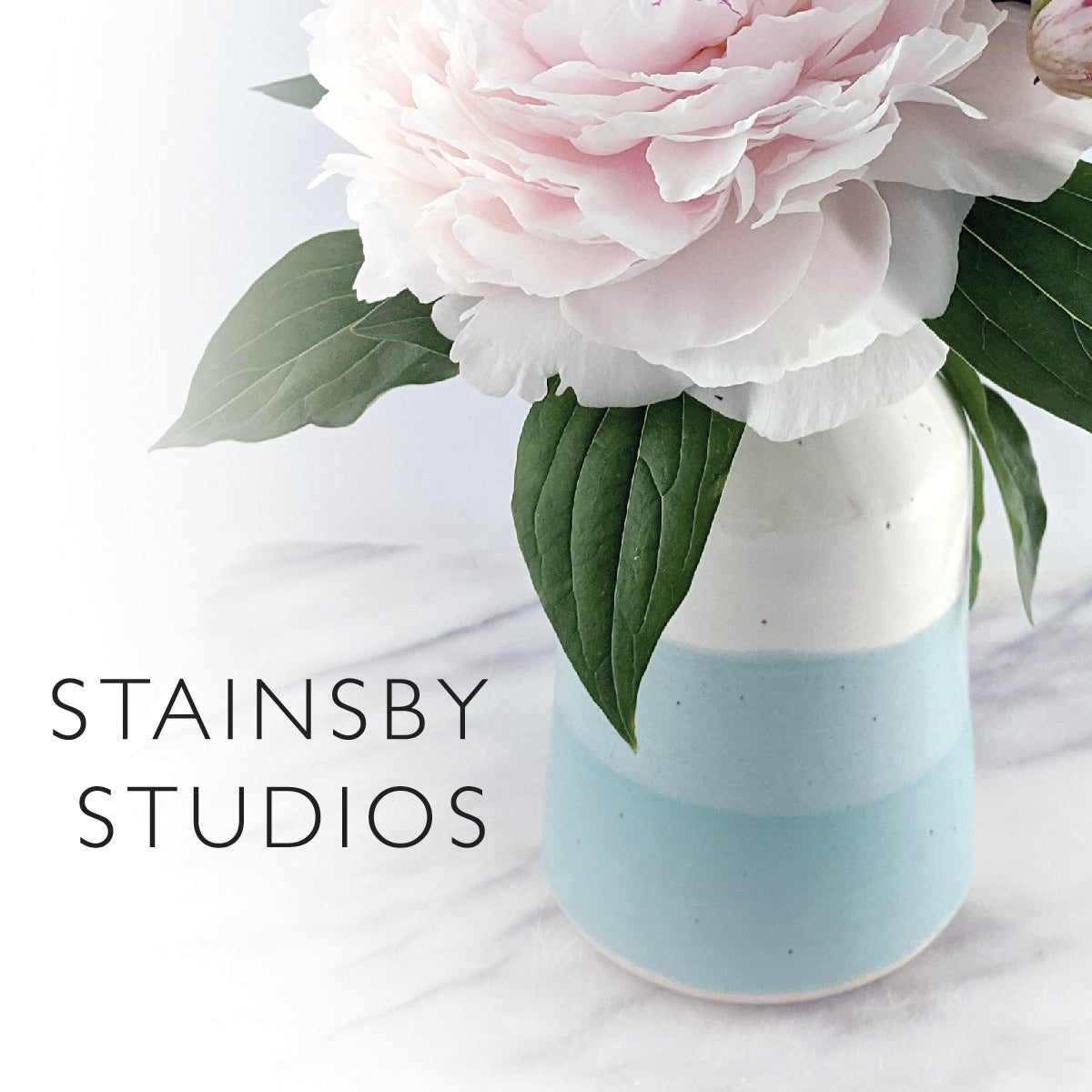 Beautiful white and turquoise vase holding a pink peony with the text Stainsby Studios on the bottom left