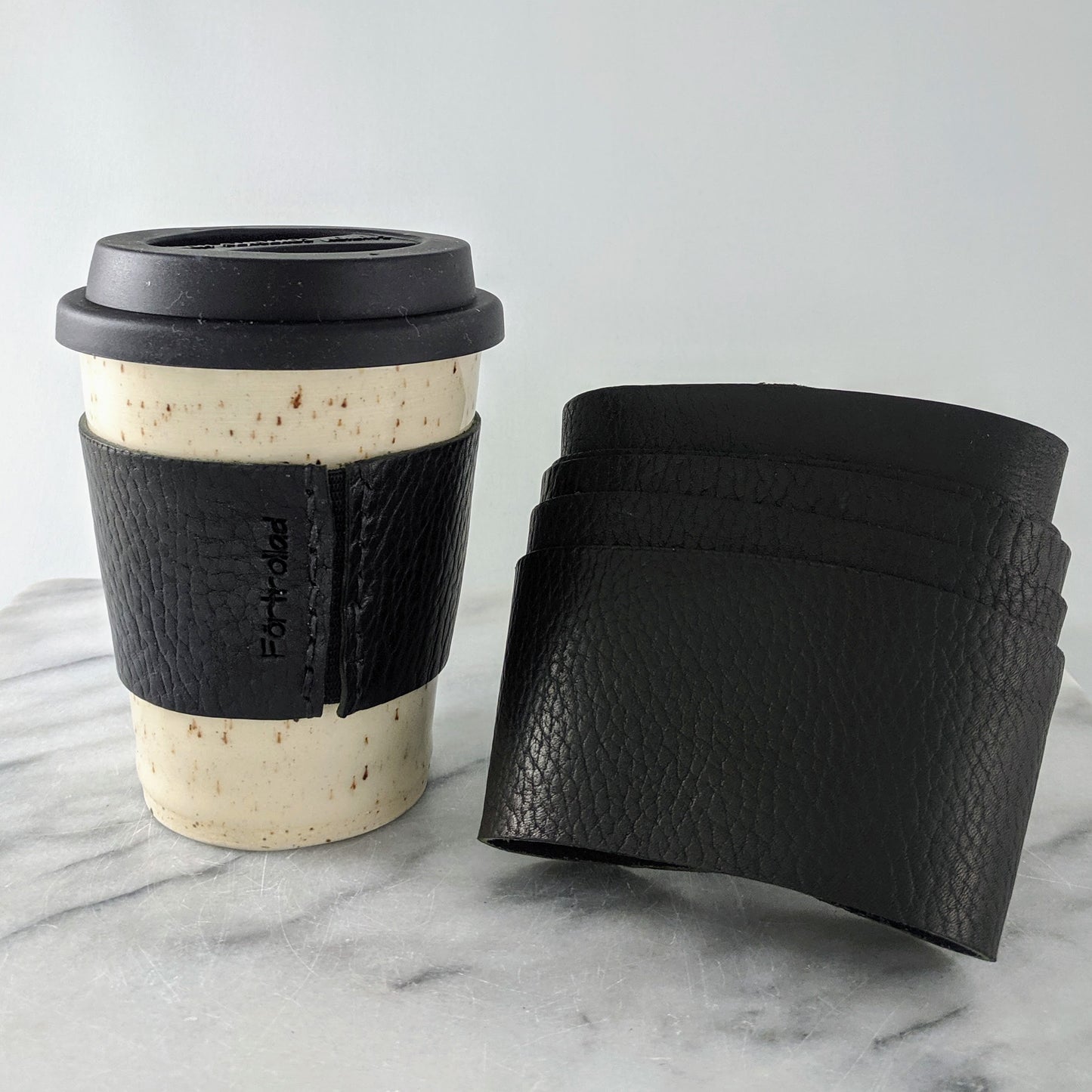 Black leather sleeves for travel mugs, used to protect your hand from the warm ceramic mug during use.